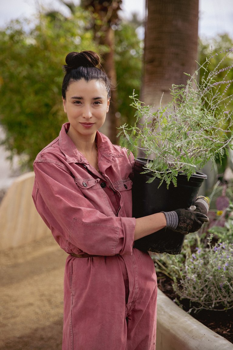 Lily Kwong in pink jumpsuit holding potted plant